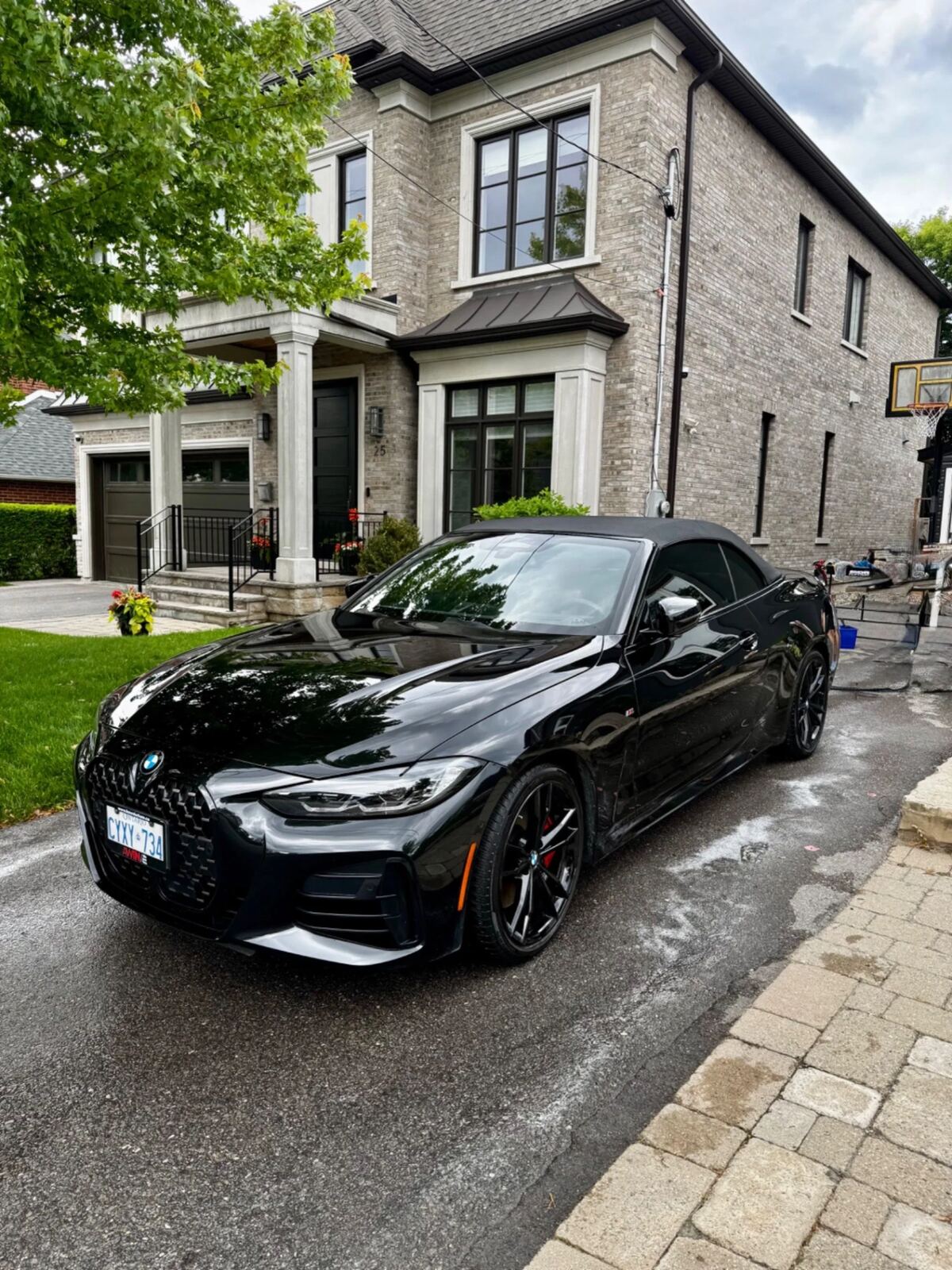 Freshly detailed black BMW M440i convertible parked in a Toronto driveway with a glossy mirror finish